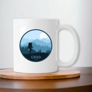 Mug blanc sur un plateau GR20 avec silhouette de randonneur et paysage de montagne stylisé